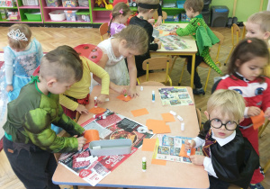 Dzieci z grupy 2 smarują klejem papierowe cegiełki